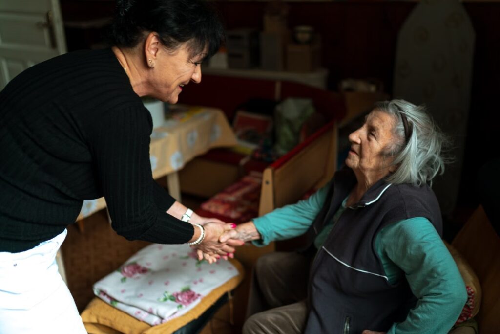 Caregiver greeting an older woman at home.