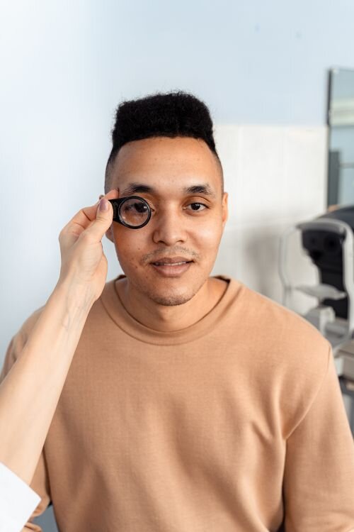 Patient having his vision assessed with a handheld examination lens