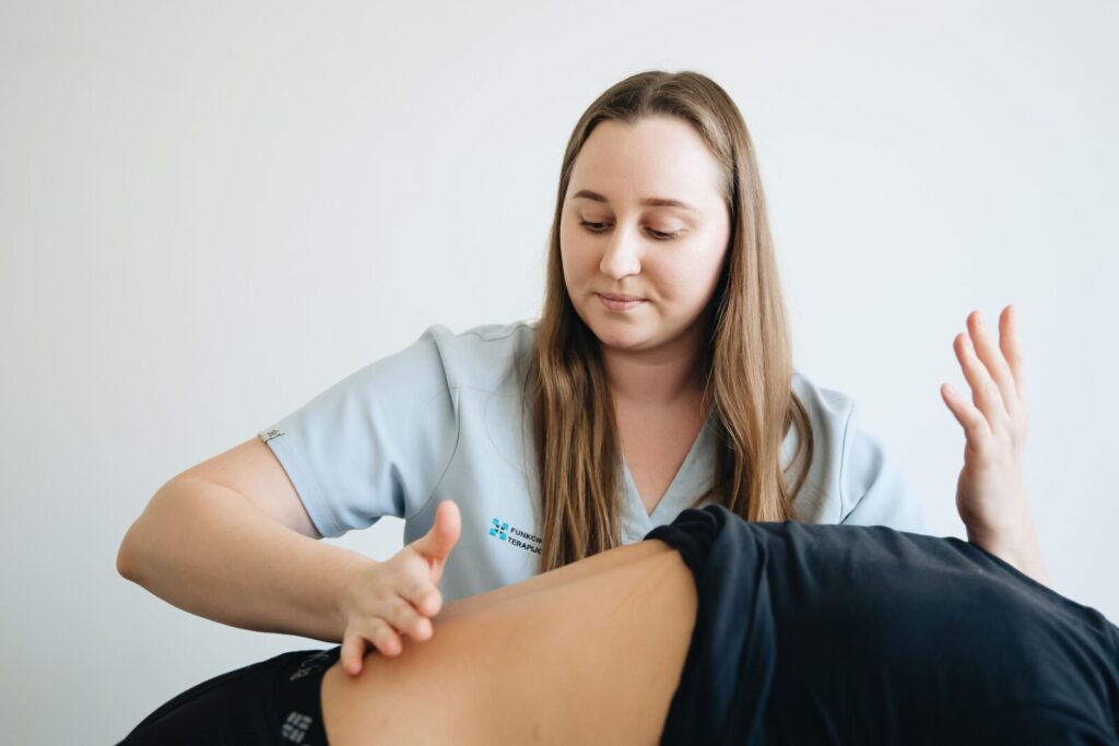 Therapist in clinical uniform applying hands-on massage to a patient’s back