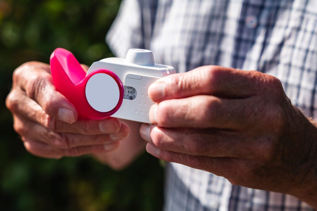 Close-up of an older person’s hands holding an inhaler.